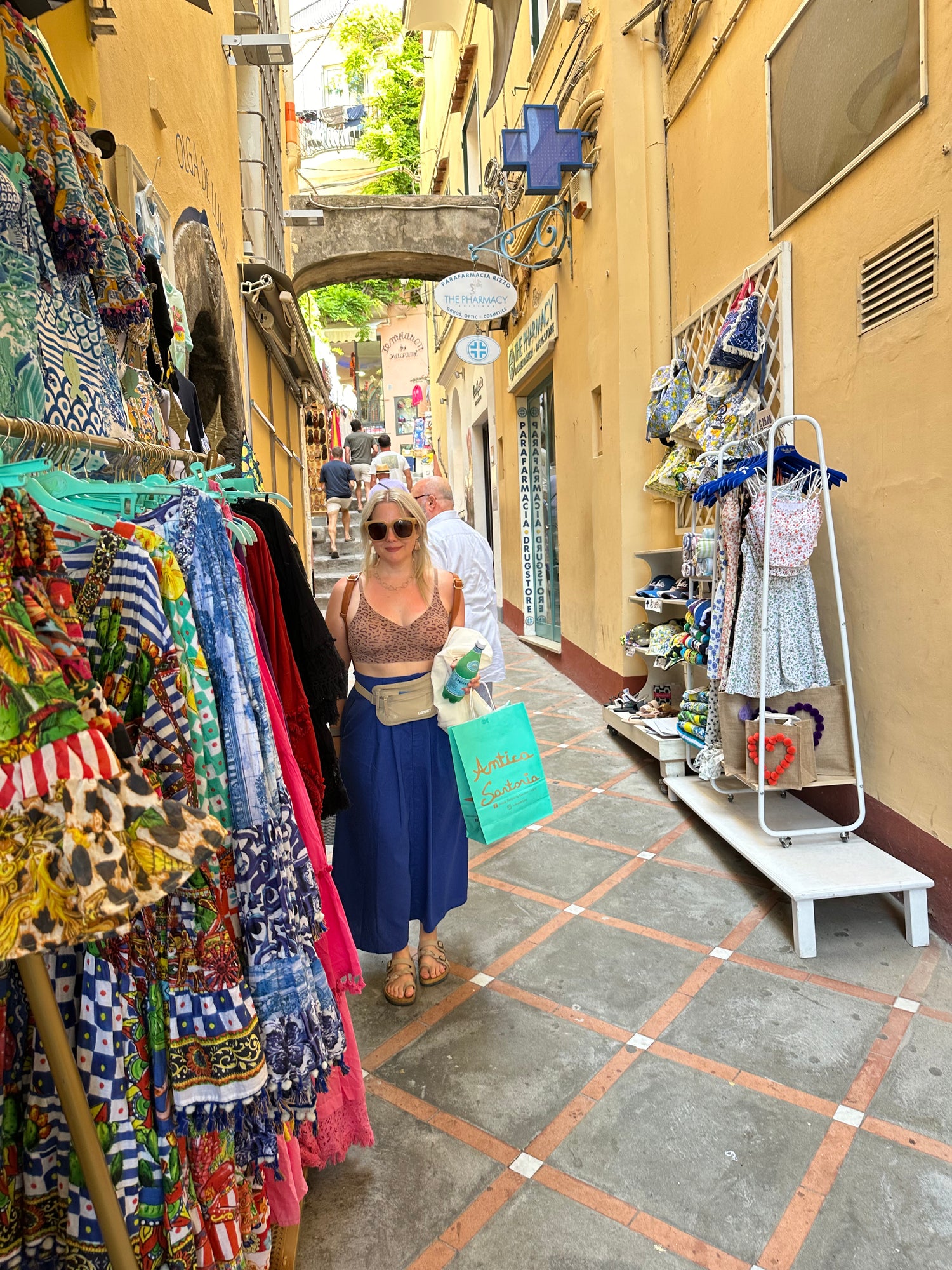 Julie Godsey, a blonde woman in her 40's stands on a narrow shop lined street in the colorful coastal village of Positano, Itay.