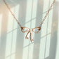 gold bow necklace with light green shadowy background