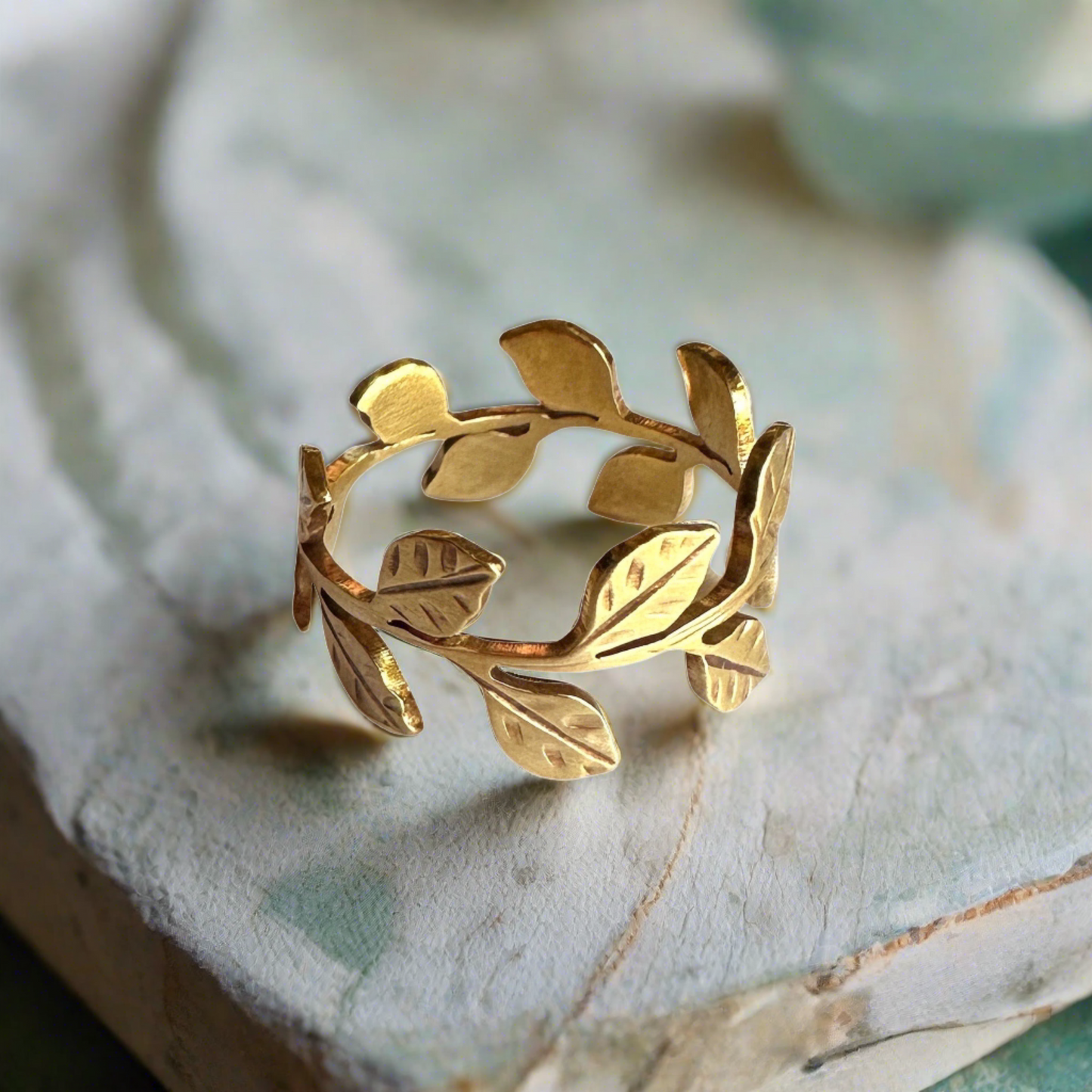 gold vine leaf ring with soft creams and sea foam green background