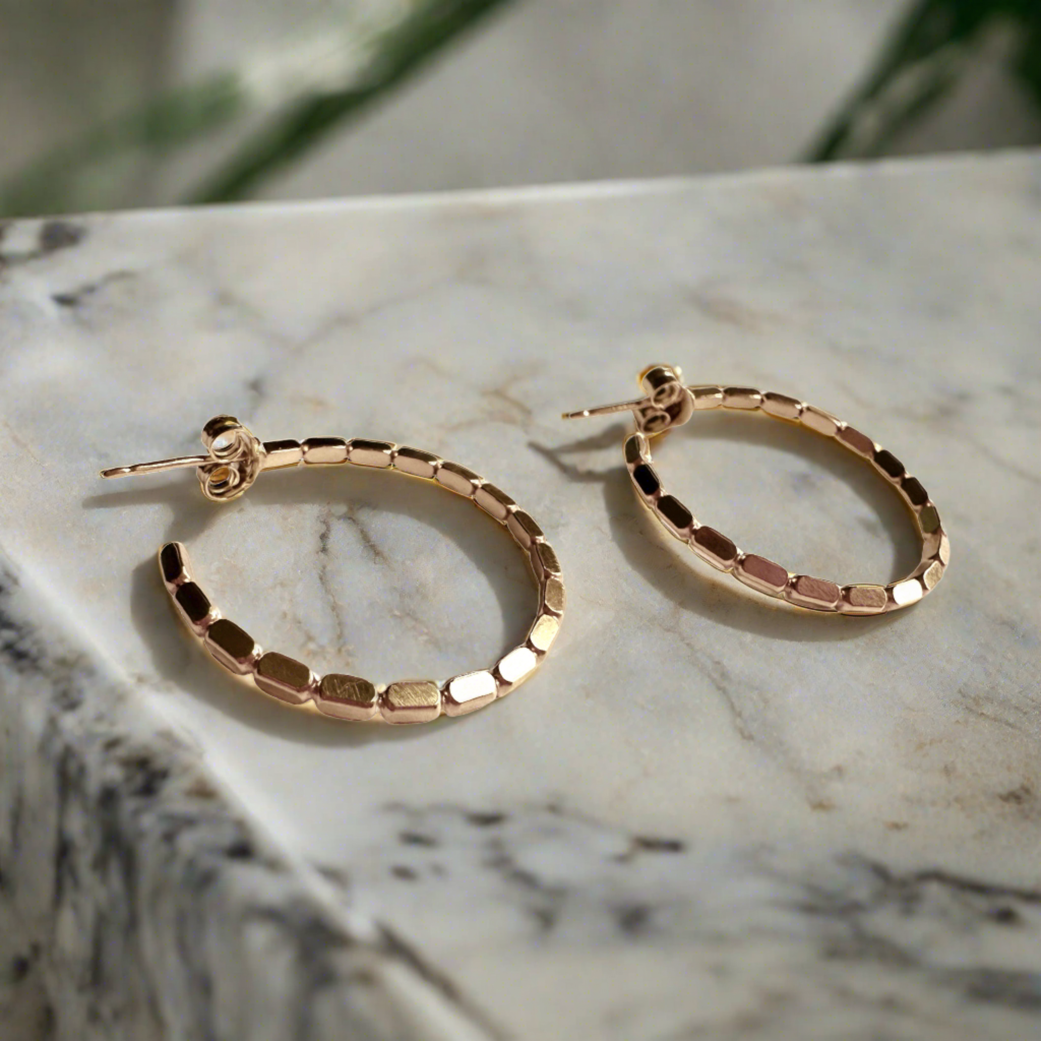 gold hoop earrings on a modern marble background