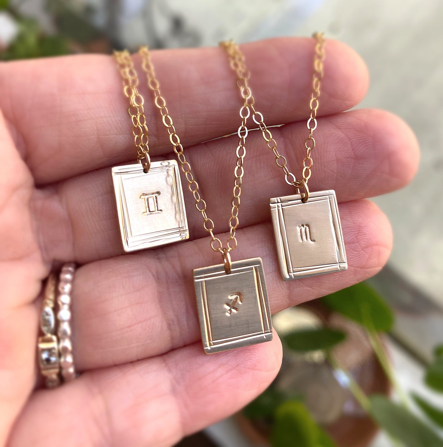 custom zodiac sign necklaces in gold filled draped across a hand