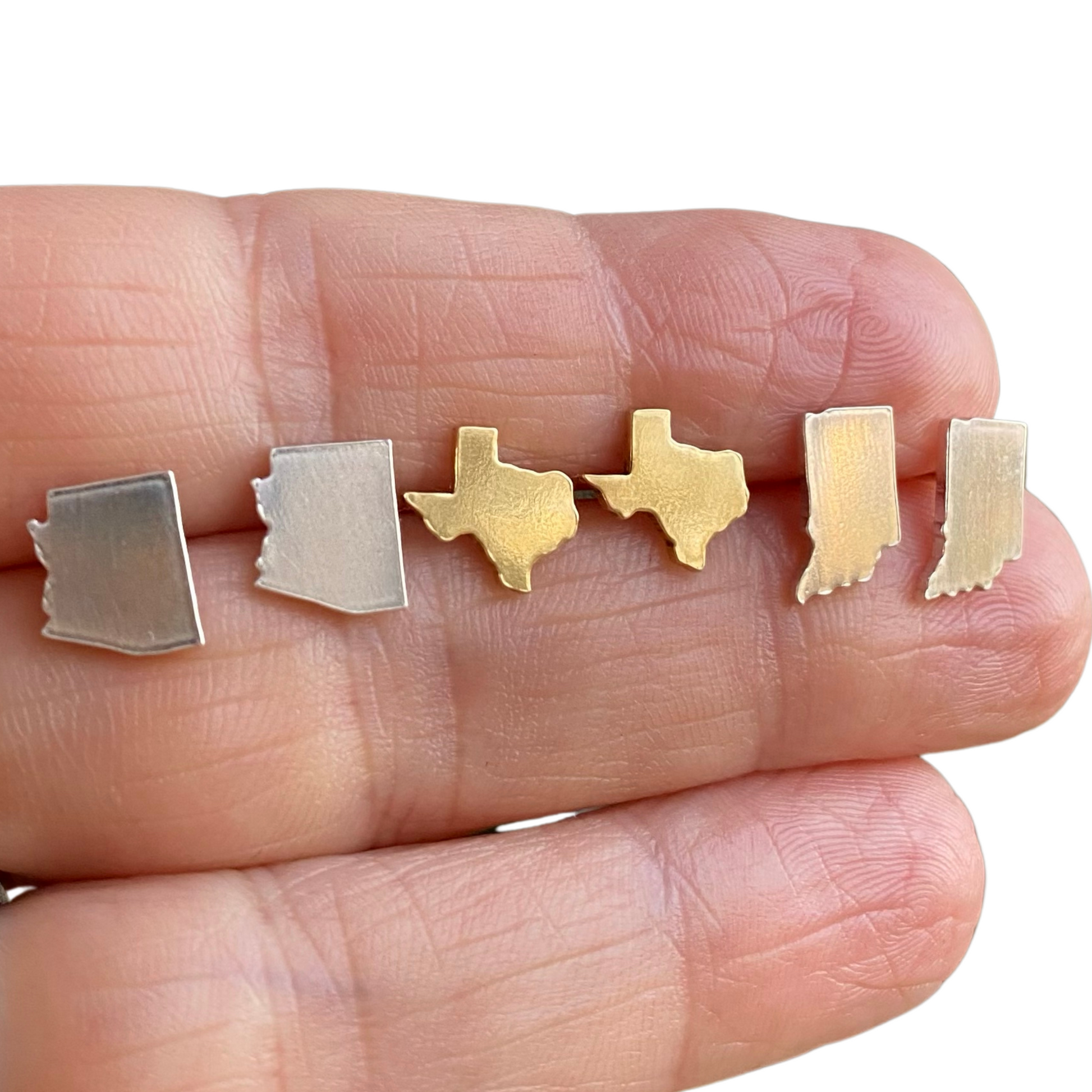 state outline earrings featuring Arizona earrings, Texas earrings and Indiana earrings in gold and sterling silver displayed across a hand