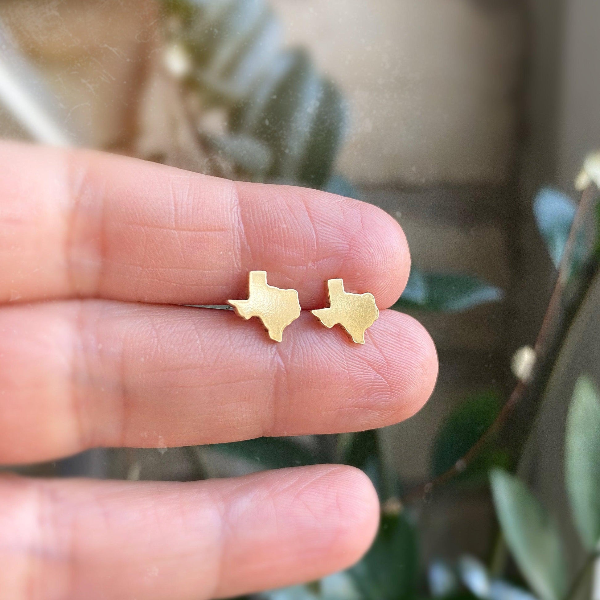 gold texas studs displayed on a hand